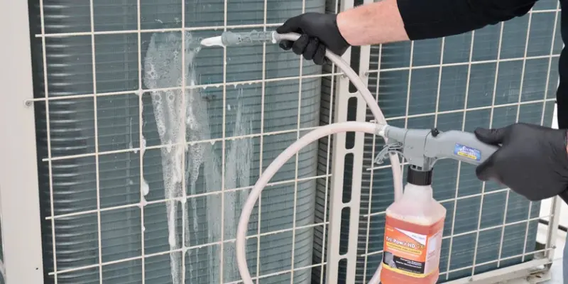 Technician cleaning outdoor AC condenser coil