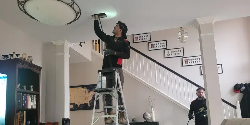 Technician cleaning ceiling air duct inside home