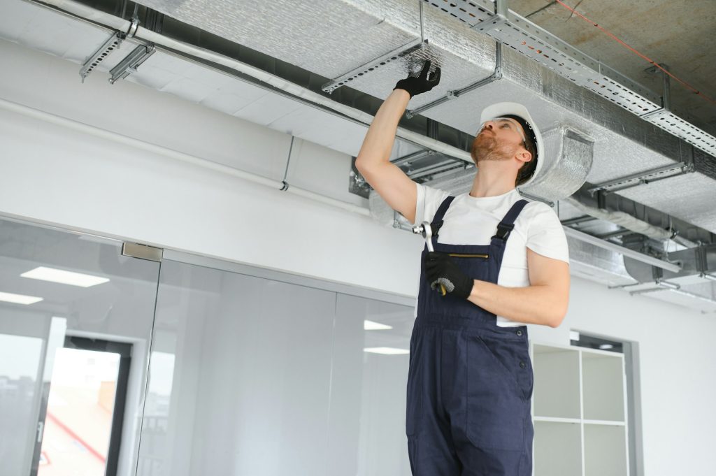 Caucasian HVAC Technician Worker in His 40s Testing Newly Installed Warehouse Ventilation System.